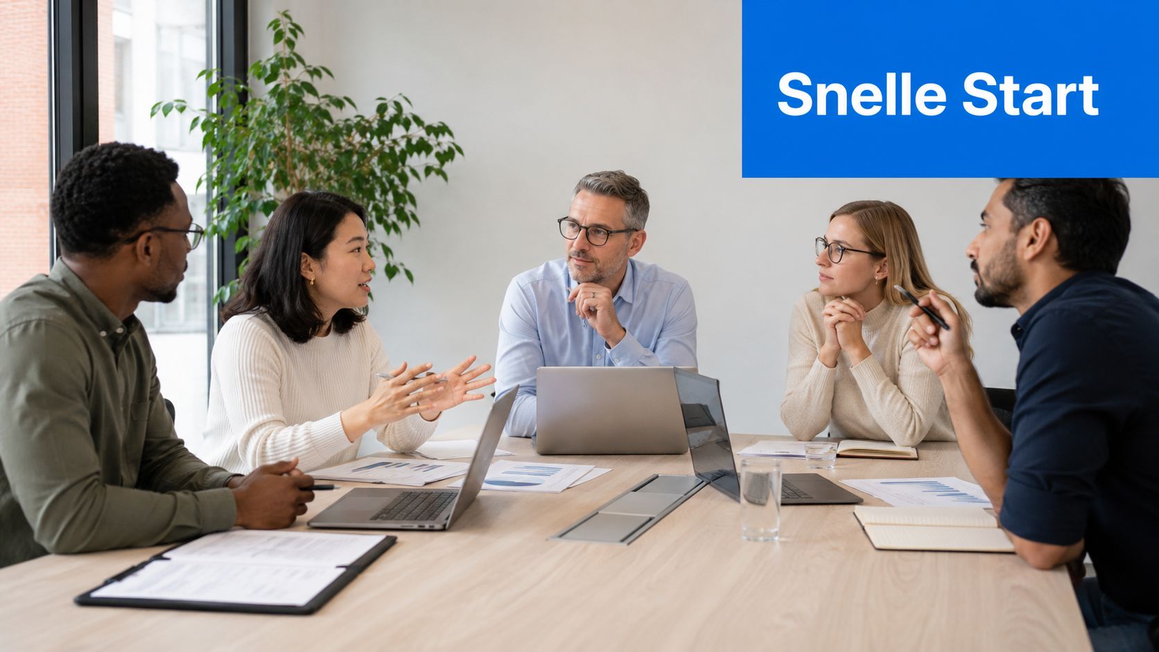 Een divers team van professionals voert een productieve werkvergadering aan een tafel met laptops en documenten.